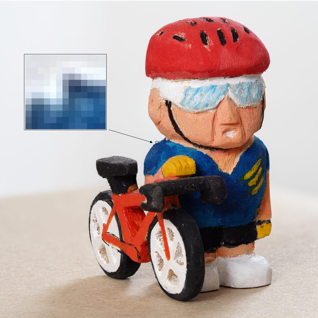 Image of a wooden model with a cut-out of a small section showing pixels on an edge